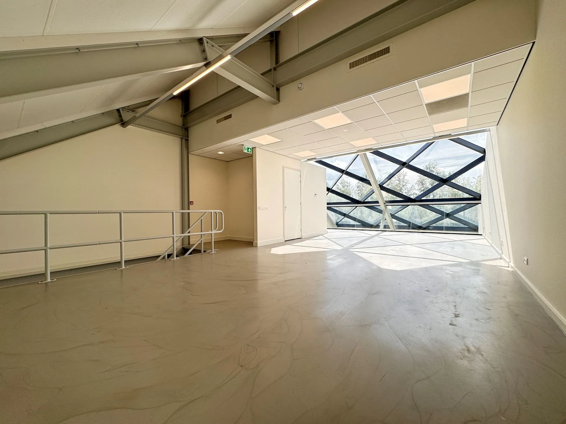 Lichte, lege ruimte in het Mart Stamhof met een schuine glazen gevel en metalen dakconstructie.